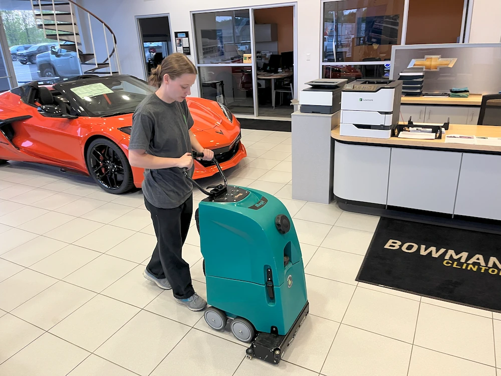 Janitorial cleaner using professional floor polishing machine on new car showroom floor