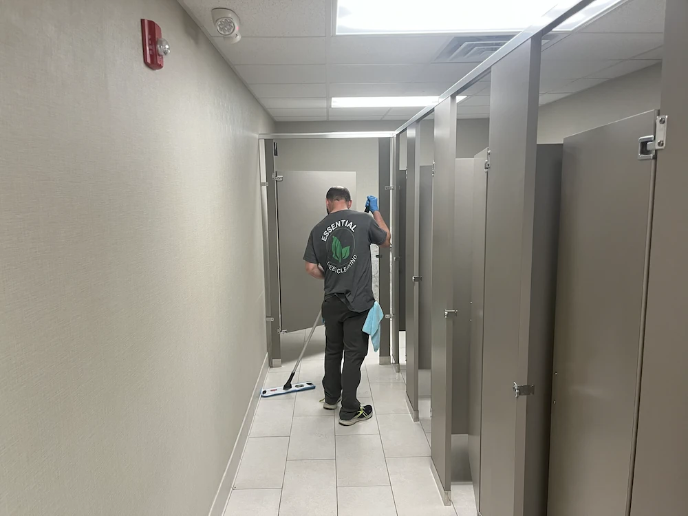 Janitorial cleaning team member properly cleaning bathroom floor