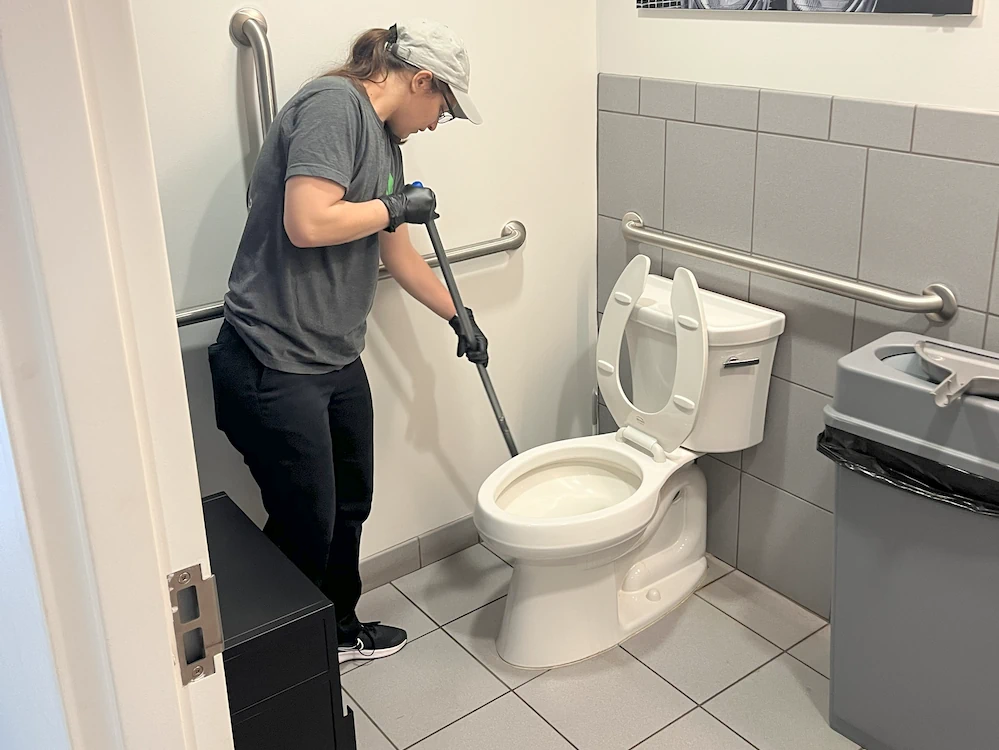 Janitorial cleaner mopping bathroom floor in commercial building