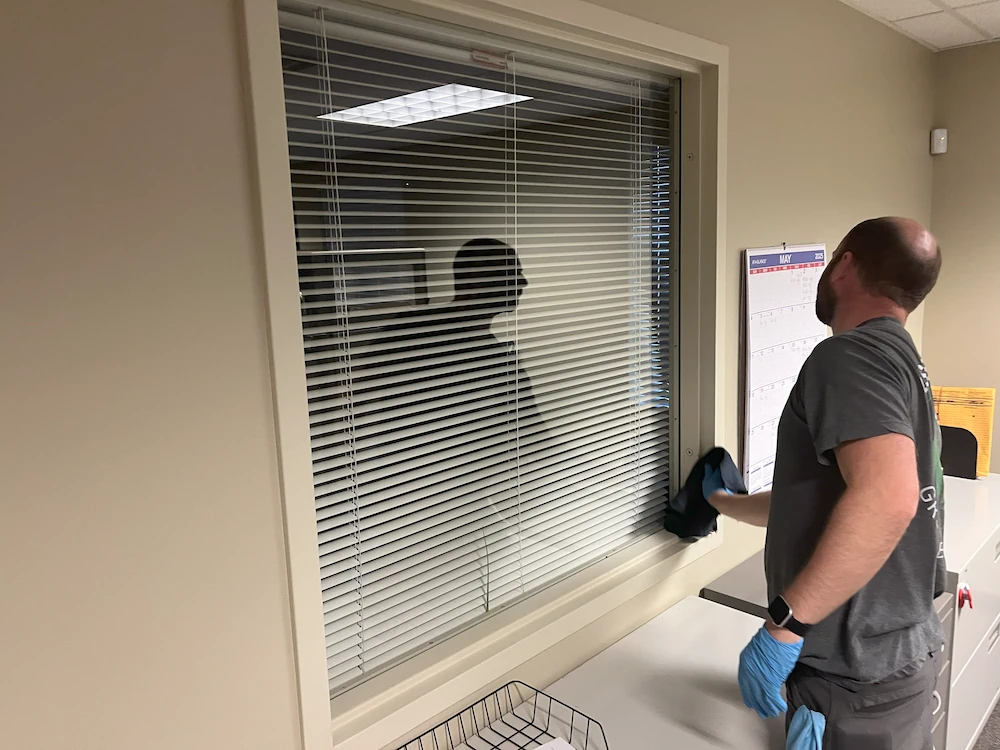 Janitorial worker cleaning interior window in medical therapy clinic
