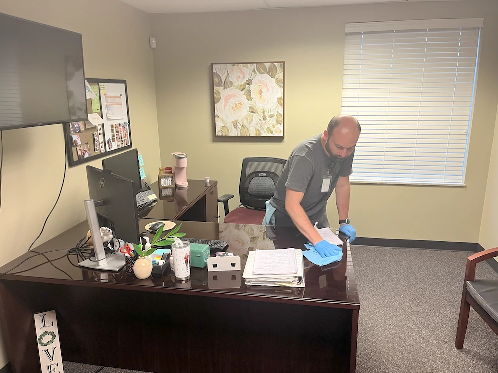 Janitorial cleaning working dusting desk in financial office