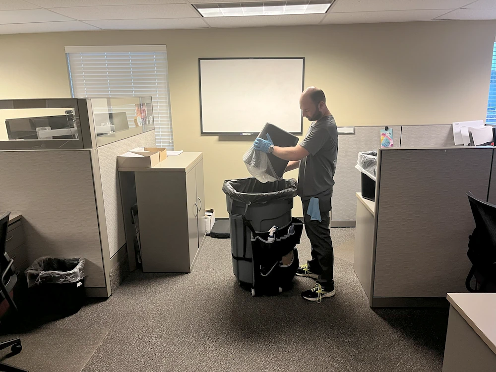 Janitorial cleaner emptying office trash after business hours